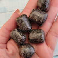Tumbled green nuummite coppernite stones in hand