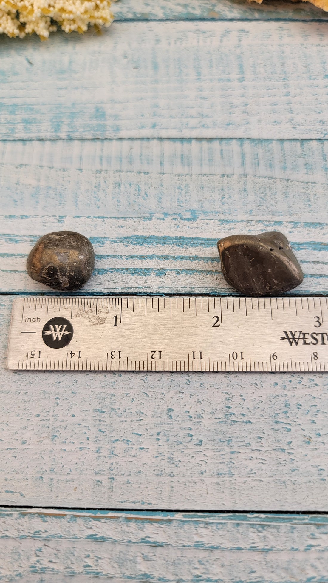 ruler comparing sizes of tumbled pyrite