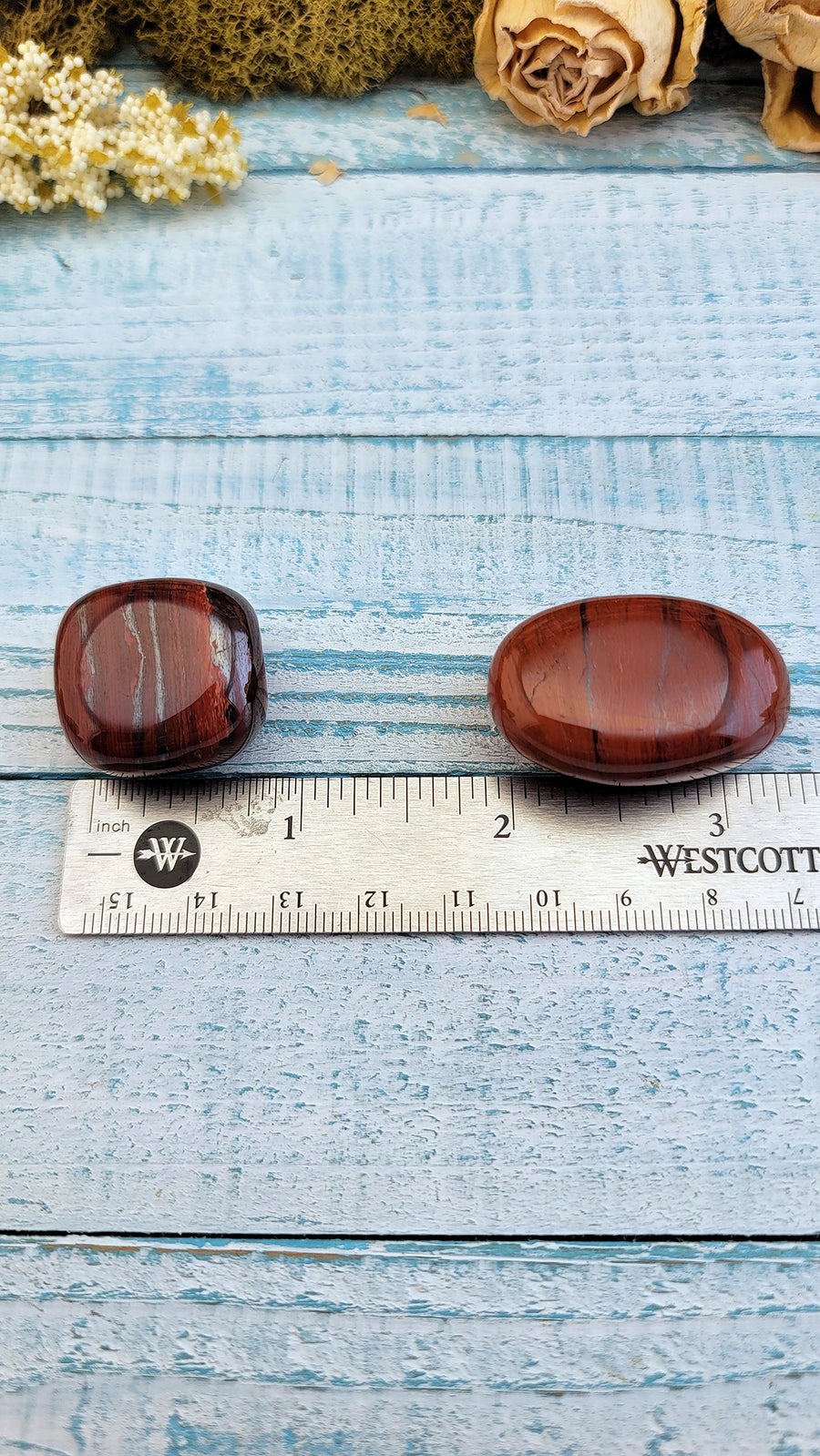 tumbled red silver leaf jasper stones on ruler for measurement