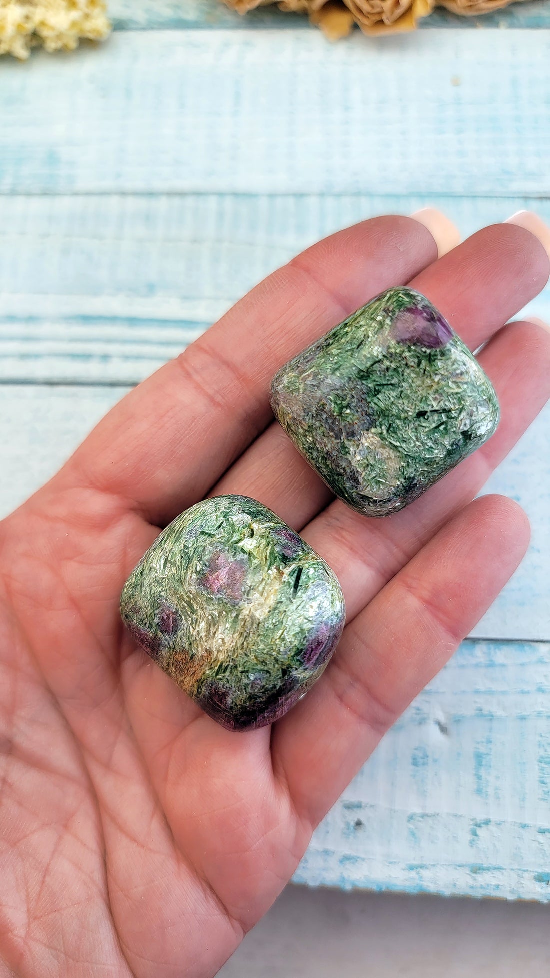 two tumbled ruby kyanite fuchsite crystal pieces in hand