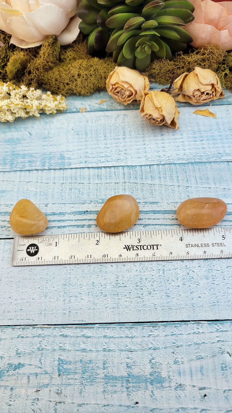 tumbled yellow aventurine crystal pieces on ruler for measurement