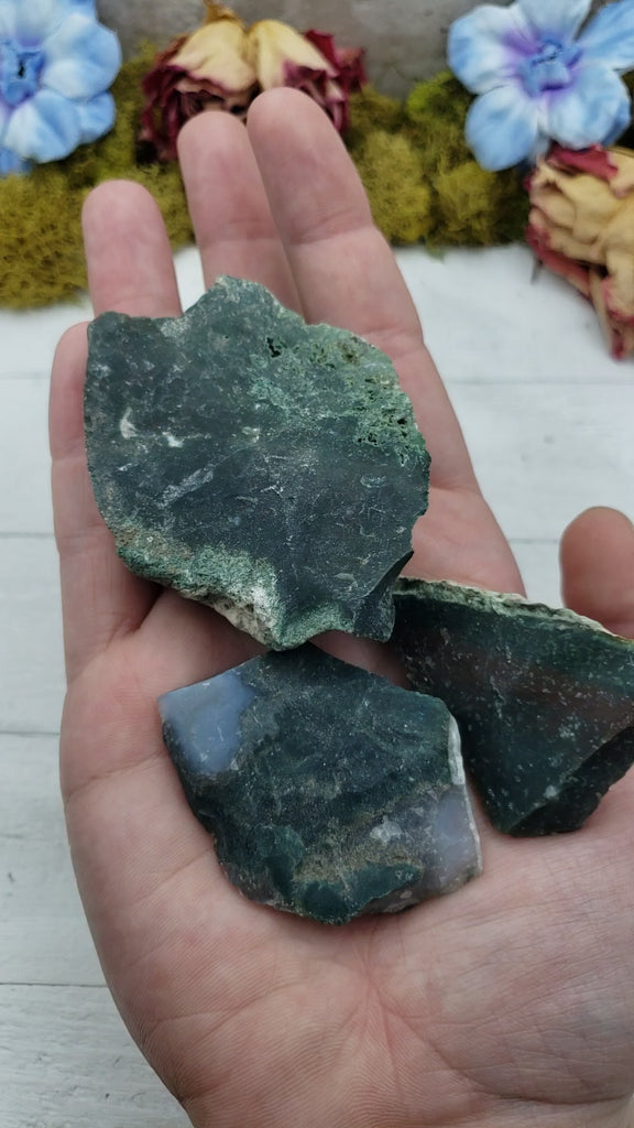 Video of hand holding three rough bloodstone crystal stones.